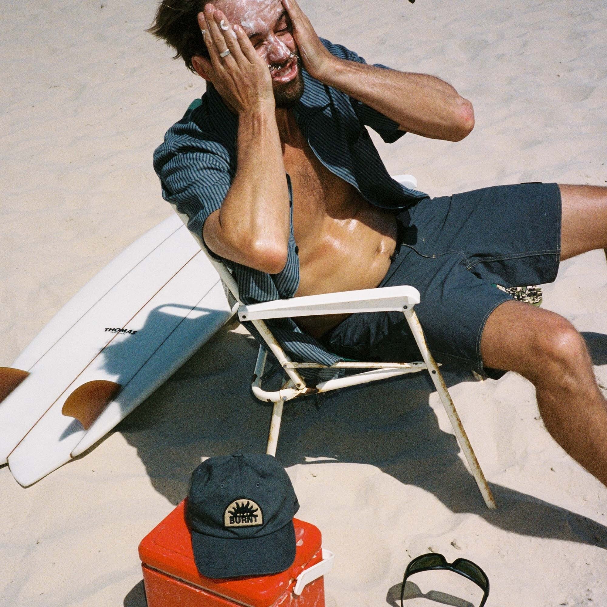 Man sitting in summer setting wearing Roark Burnt Collection boardshorts, highlighting adventurous outdoor lifestyle